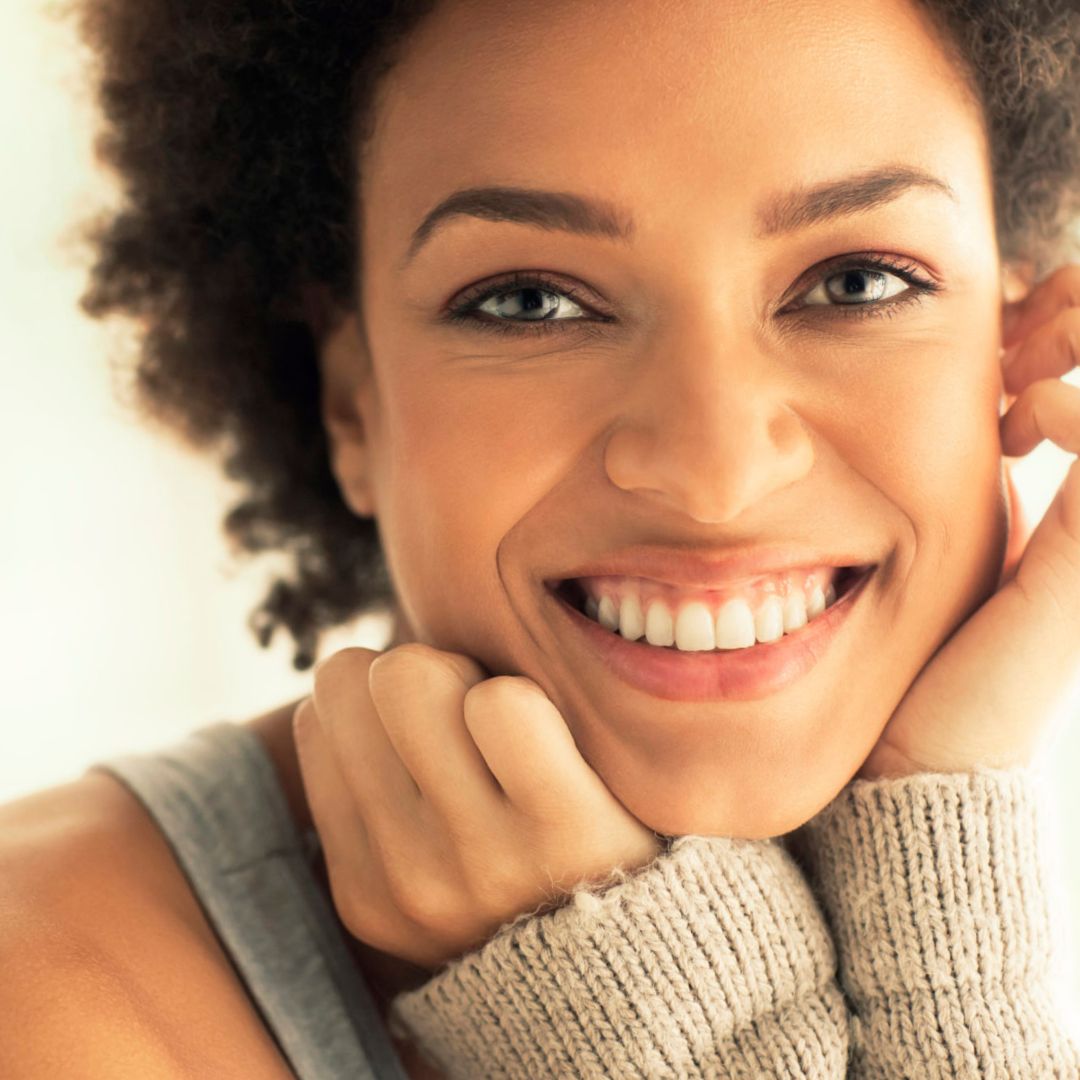 Mulher sorrindo mostrando os dentes brancos após clareamento dental.